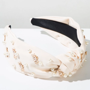 Détail d'un serre-tête torsadé crème avec perles blanches et lettres LOVE dorées