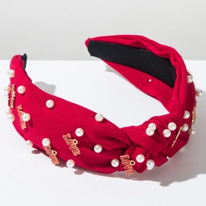 Détail du serre-tête rouge torsadé avec perles blanches et pendentifs LOVE dorés