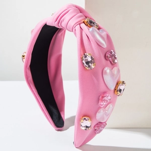 Detailaufnahme von rosa Stoff-Haarreif mit funkelnden Strasssteinen und glitzernden Herzanhängern