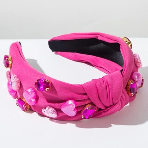 Detailaufnahme von geknotetem rosa Haarreif mit Strasssteinen und Herzanhängern
