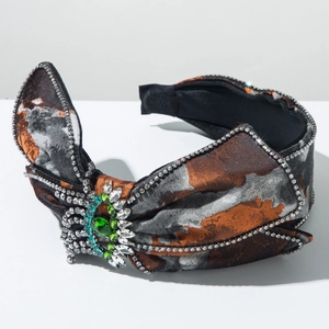 Détail du serre-tête en satin fleuri avec grand joyau vert et strass marquise