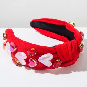 Detail eines roten Knotenstirnbands mit rosa Herzanhängern und roten Glitzersteinen