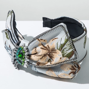 Détail d'un serre-tête vintage avec broderie florale bleue et strass émeraude