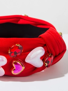 Detailaufnahme des roten Stoffhaarbands mit glitzernden Herzen und roten Schmucksteinen
