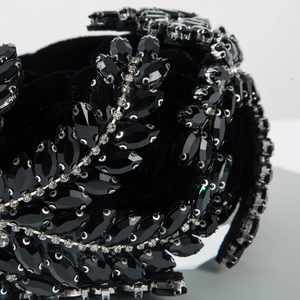 Gros plan sur un serre-tête en velours noir orné de feuilles de cristal et de strass brillants