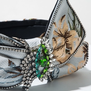 Détail d'un serre-tête floral vintage avec cristaux émeraude et bordure strass