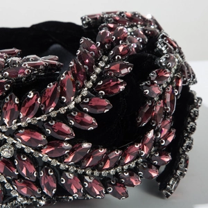 Détail macro du serre-tête en velours noir avec cristaux violets et motifs de feuilles strass
