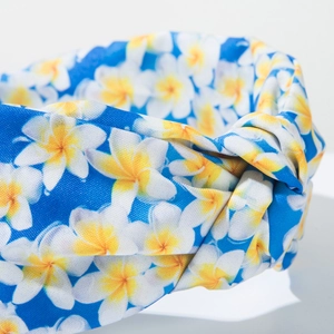Detailed macro view of blue knotted headband featuring white plumeria floral patterns