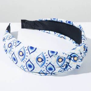 Nahaufnahme des breiten geknoteten Stirnbands mit blau-gelbem Evil Eye Stoffmuster