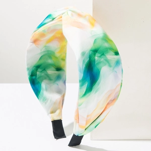 Détail du bandeau en tissu tie-dye coloré avec un large nœud sur fond minimaliste