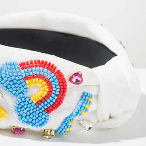 Detailed close-up of white velvet headband with colorful beads and rhinestone flowers