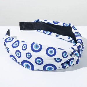 Nahaufnahme des blauen Evil Eye Musters und Knotens auf dem weißen Stoffstirnband