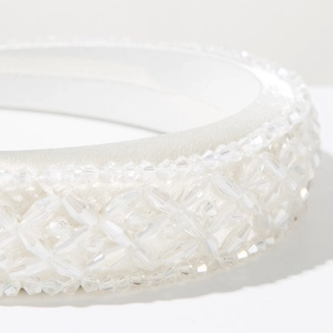 Macro detail of hand-sewn crystal beads and luxury white satin on a padded headband