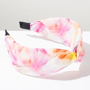 Détail du bandeau tie-dye bohème avec nœud floral rose et orange sur un fond blanc épuré