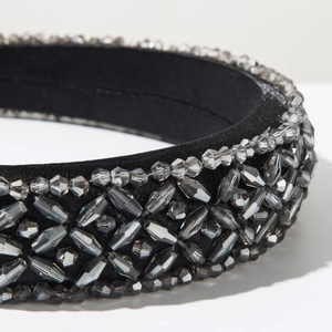 Detailed close-up of hand-sewn grey and clear crystals on a black wide fabric headband