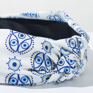 Detailaufnahme des Knotens und blauen Evil-Eye-Prints auf weißem Stoffstirnband