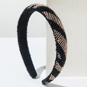 Détail de perles de rocaille champagne et noires sur une surface de serre-tête rembourré