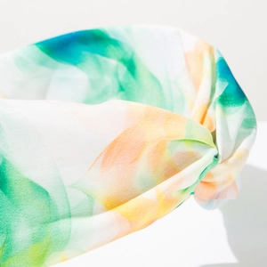 Détail d'un bandeau bohème noué tie-dye avec des motifs d'aquarelle émeraude et orange vifs