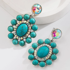 Detailopname van vintage oorbellen met ovale turquoise steen en kleurrijke strasaccenten