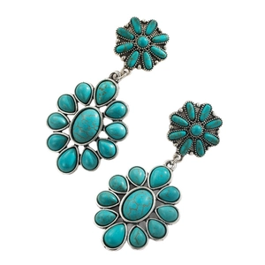 Detail van bohemien turquoise hangende oorbellen met een zilveren metalen bloembasis