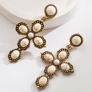 Close-up of vintage gold cross earrings with white turquoise stones and bead textures