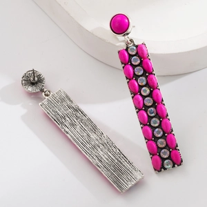 Macro detail of vintage bohemian long earrings with rose red stones and silver alloy