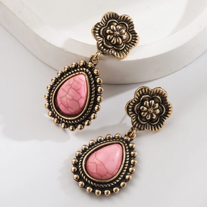 Détail de boucles d'oreilles goutte d'or vintage avec pierres roses marbrées