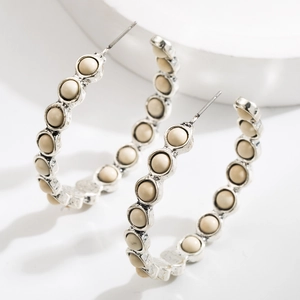 Silver wavy hoop earrings featuring matte cream beads in a retro geometric design