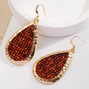 Sparkling red sequin teardrop earrings with golden hammered metal frames on a tray