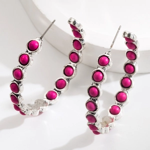 Detail of vintage silver hoop earrings with magenta matte beads on white platform