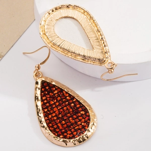 Detail view of teardrop earrings with gold hammered texture and orange glitter inlay
