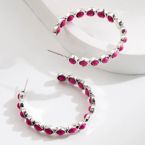 Detailed view of silver C-hoop earrings with pink turquoise stones on white pedestal
