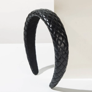 Quilted black leather padded headband with elegant diamond stitching on a white stand