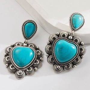Detail of bohemian turquoise drop earrings featuring vintage silver engraving and heart stones
