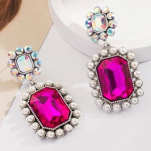 Détail de boucles d'oreilles bohèmes avec cristal magenta et petites perles