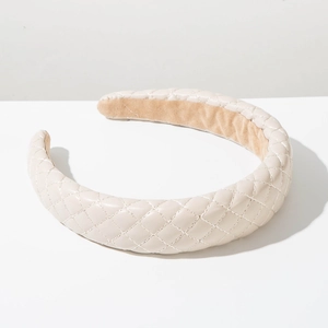 Detailed macro view of cream faux leather wide headband with quilted diamond pattern texture