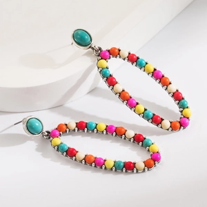 Detail of bohemian drop earrings with colorful beads and turquoise stone on a pedestal