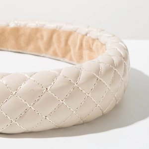 Detailed macro view of cream faux leather headband with luxury quilted diamond pattern