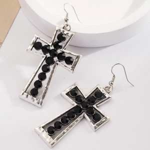 Pendientes de cruz de plata vintage con piedras negras y gancho en fondo blanco
