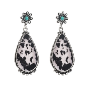 Detail view of silver floral stud with turquoise stone and cow print leather drop pendant