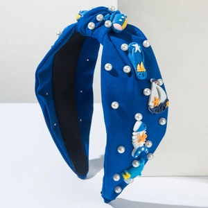 Détail d'un serre-tête nautique bleu marine avec perles, voilier et baleine en résine