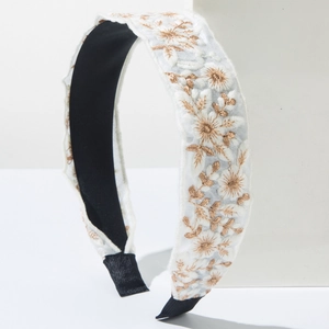 Detail of bohemian floral embroidery with gold-brown threads on a wide white headband