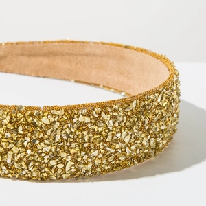 Détail d'un serre-tête large orné de pierres dorées et d'une doublure douce en daim kaki