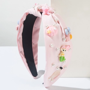 Détail du bandeau en tissu rose avec sirène, coquillages en résine et perles blanches