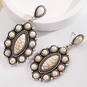 Detailed macro view of vintage silver earrings with white marble texture stones and ornate metalwork