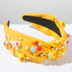 Détail d'un bandeau jaune avec des figurines marines en résine et des perles blanches
