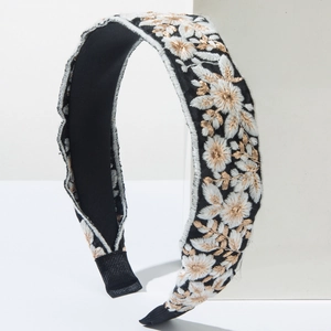 Close-up of bohemian headband with detailed white and gold floral embroidery on black fabric