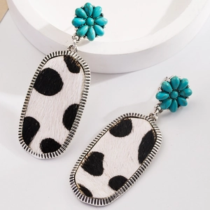 Vue détaillée de boucles d'oreilles bohèmes avec fleur turquoise et motif vache