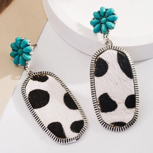 Vue détaillée de boucles d'oreilles bohèmes avec fleurs turquoise et texture cuir imprimé vache