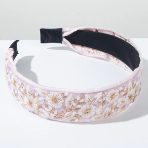 Close-up of pink satin headband with white floral embroidery and black velvet lining